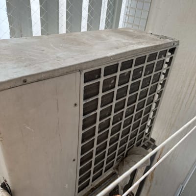 יחידת מזגן חיצונית עם סורגי אוורור על קיר חיצוני