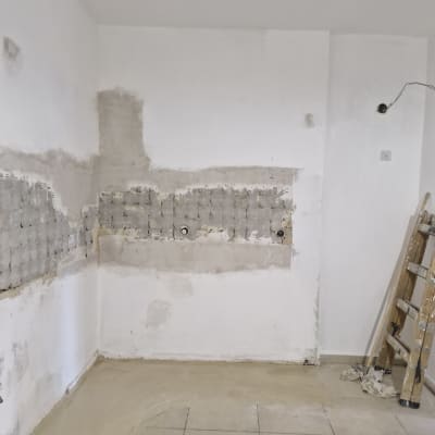 קיר עם טיח מתוקן, סולם עץ, רצפה מרוצפת