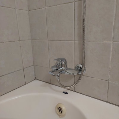 ברז אמבטיה עם צינור מקלחת על קיר אריחים