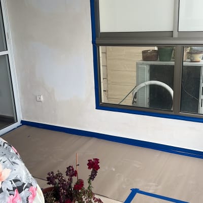 קיר צבוע חלקית עם מסקנטייפ כחול מסביב לחלון