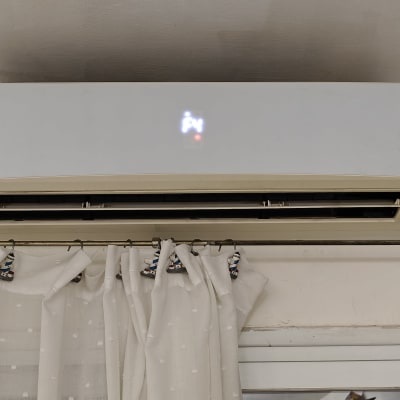 מזגן קיר לבן מותקן מעל וילון לבן