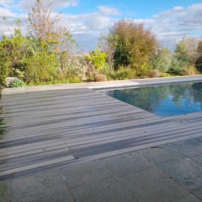 דק עץ ובריכה בגינה עם צמחייה מסביב