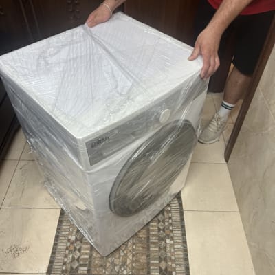 אדם מזיז מכונת כביסה עטופה בניילון