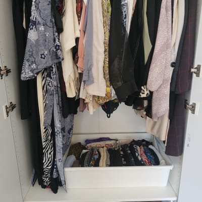 ארון בגדים מאורגן עם בגדים תלויים ומגירות נעליים