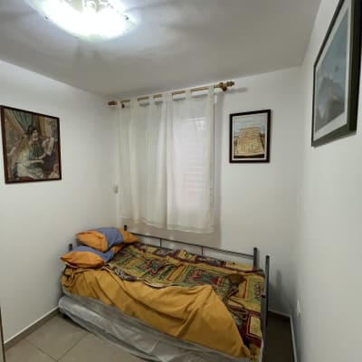 חדר שינה עם מיטה, וילון ותמונות על הקיר