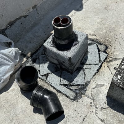 צינור שחור על גג עם חומר איטום סביבו