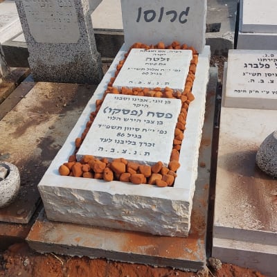 מצבות עם כיתוב בעברית ואבנים קטנות על הקברים