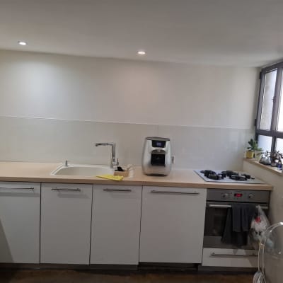 מטבח עם משטח זכוכית, כיור וברז, מכונת קפה ותנור