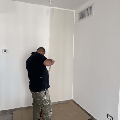 אדם צובע קיר בחדר עם מברשת צבע