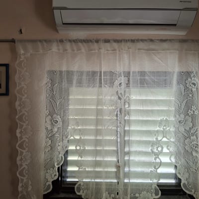 מזגן תלוי מעל חלון עם וילון תחרה