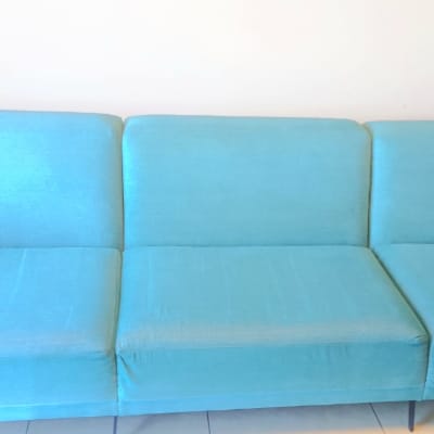 ספה כחולה נקייה עם כריות ישיבה ומשענות ידיים.