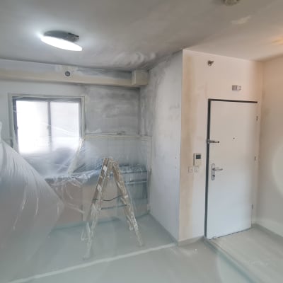 סולם ויריעות פלסטיק בחדר צבוע חלקית