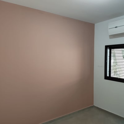 קיר צבוע בצבע ורוד עם חלון ומזגן