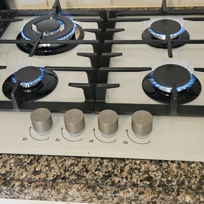 כיריים גז עם להבות דולקות על משטח שיש במטבח