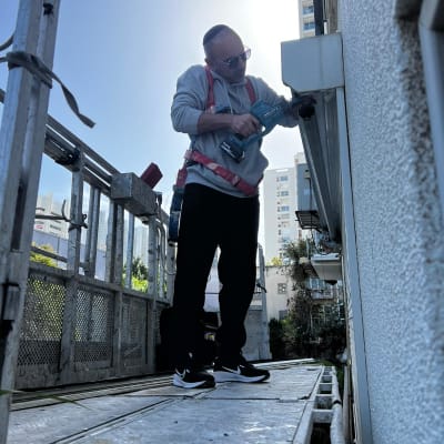 אדם מתקין תריסים על פיגום חיצוני