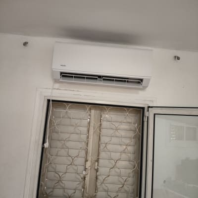 מזגן מותקן מעל חלון עם סורגים