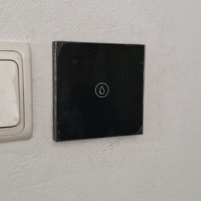 מתג חשמלי שחור עם סמל טיפה על קיר לבן