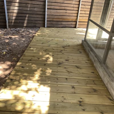 דק עץ חדש ליד גדר עץ בגינה