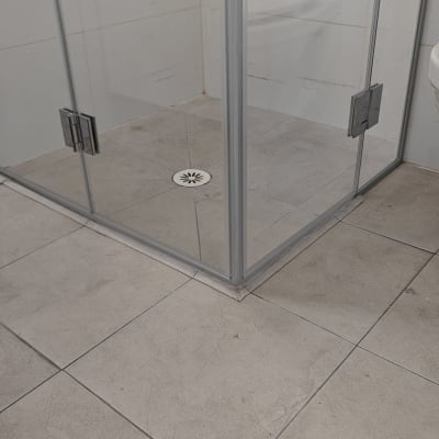 מקלחון זכוכית עם רצפת אריחים וניקוז עגול