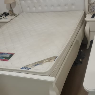 חדר שינה עם מיטה ומזרן לבן, שולחן עם חפצים שונים