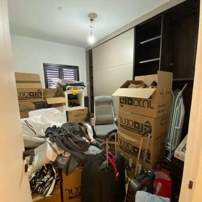 חדר מלא בארגזים, מזוודות ובגדים מפוזרים