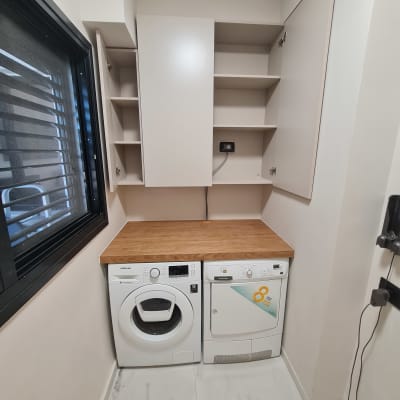 ארון עץ עם מדפים פתוחים מעל מכונת כביסה