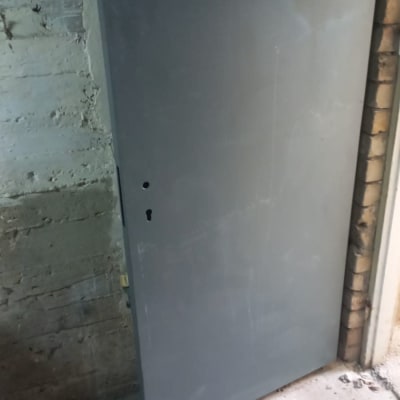 דלת מתכת אפורה על רקע קיר בטון