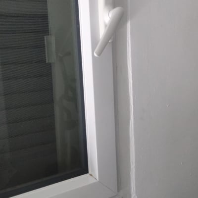 חלון עם ידית לבנה על קיר לבן