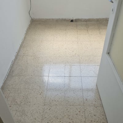חדר ריק עם רצפת אריחים נקייה ודלת פתוחה