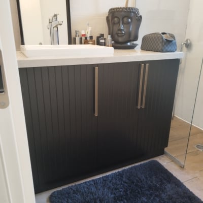 ארון עץ כהה עם ידיות מתכת בחדר אמבטיה