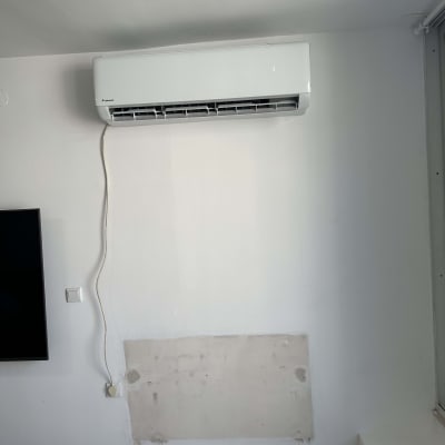 מזגן מותקן על קיר לבן עם כבל חשמל