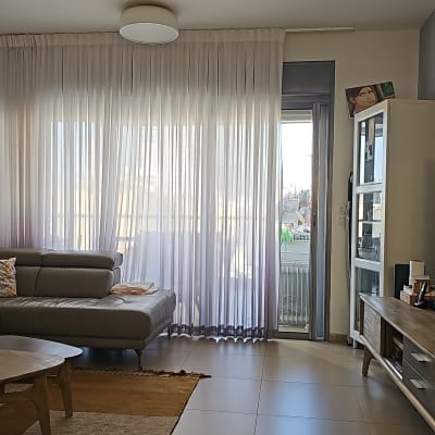 וילון לבן שקוף תלוי על חלון גדול בסלון