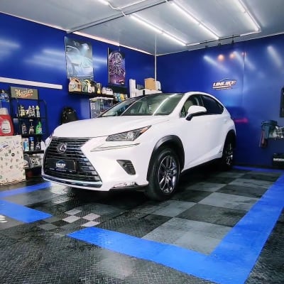 רכב לבן בחדר דיטיילינג עם ציוד ניקוי