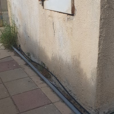 צינור מים ליד קיר עם דלת מתכת קטנה