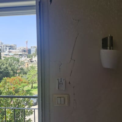 קיר עם סדקים ליד חלון ומתג חשמל