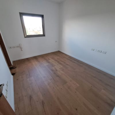 חדר ריק עם רצפת פרקט וחלון.