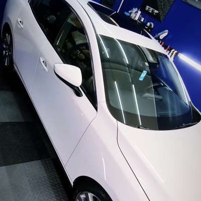 מכונית לבנה מבריקה בחדר דיטיילינג עם כלים על הקיר