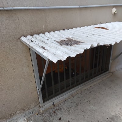 גגון מתכת מעל חלון עם סורגים