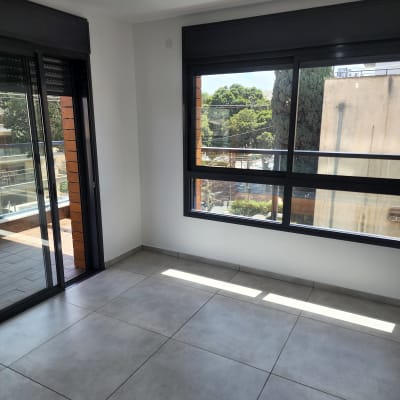 חדר ריק עם רצפת אריחים נקייה וחלונות גדולים