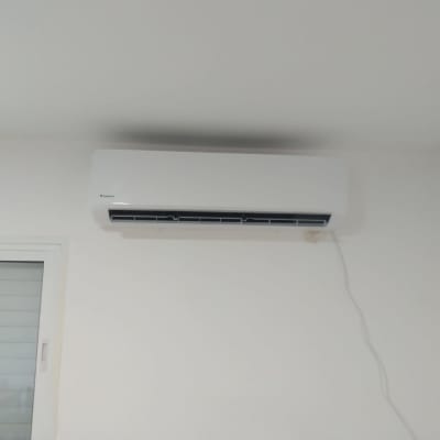 מזגן מותקן על קיר לבן עם כבל חשמל