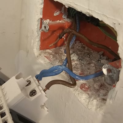 חוטי חשמל כחולים וחומים בקופסת חיבורים בקיר