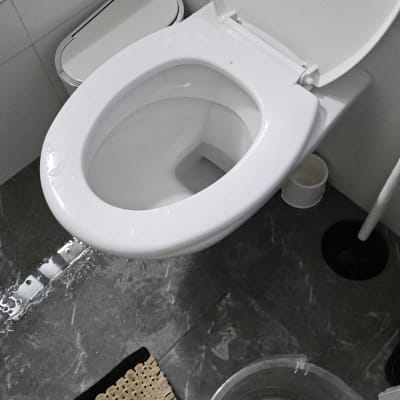 אסלה עם מים על הרצפה וכלי עבודה ליד.