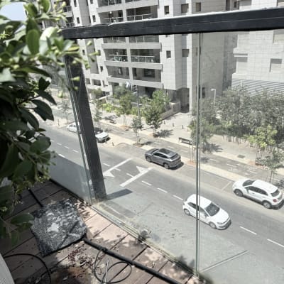 מעקה זכוכית עם כלים על רצפת עץ במרפסת