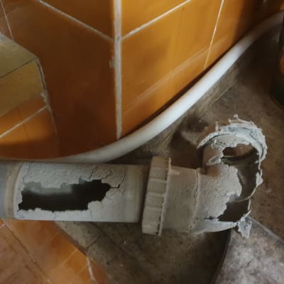 צינור פגום עם חור גדול על רקע אריחים כתומים