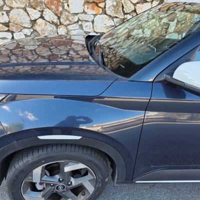 תמונה של רכב כחול עם קיר אבן ברקע