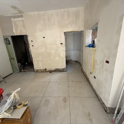 חדר בשיפוץ עם קירות מטויחים וכלים על הרצפה