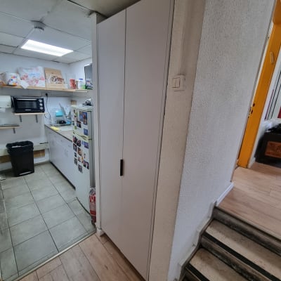 ארון לבן במטבח עם מדפים וכלים שונים