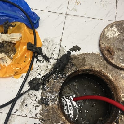 צינור אדום בתוך פתח ביוב עם מים מלוכלכים