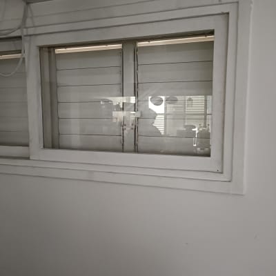 חלון זכוכית עם תריסים סגורים ומסגרת לבנה