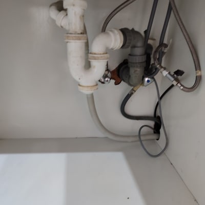 צנרת מתחת לכיור עם חיבורים וצינורות פלסטיק